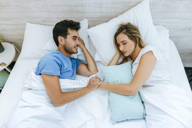 Sorrindo homem olhando para o parceiro dormindo na cama em casa — Fotografia de Stock