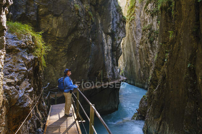 Vista lateral da mulher idosa em pé na passarela de Wasserfallsteig em Leutasch Gorge, Tirol, Áustria — Fotografia de Stock