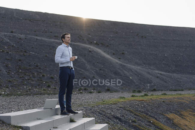 Homme d'affaires mature debout dans les escaliers sur une pointe de mine désaffectée prendre une pause café — Photo de stock