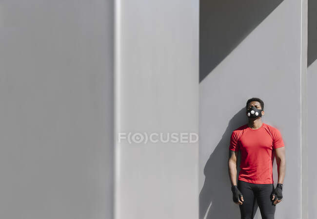 Esportista usando máscara facial inclinada na parede cinza — Fotografia de Stock