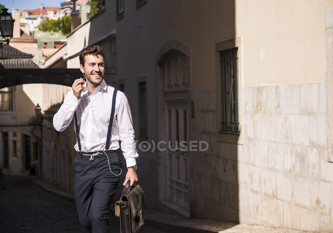 Giovane sorridente con auricolari nel centro storico, Lisbona, Portogallo — Foto stock
