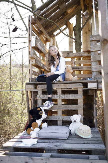 Nachdenkliches Mädchen spielt mit ihren Teddybären im Baumhaus — Stockfoto