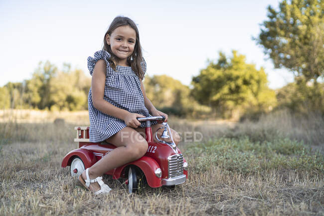 Retrato de menina sorridente com carro pedal na natureza — Fotografia de Stock