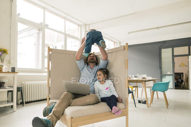 Padre jugando con dos hijas en casa oficina - foto de stock