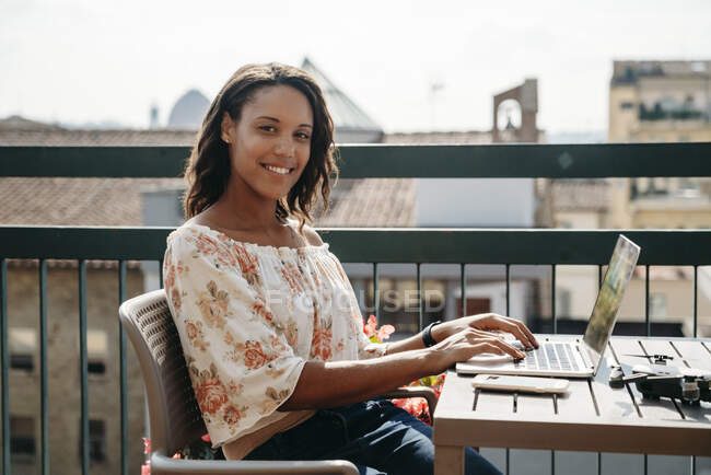Portrait of smiling young woman using laptop on a balcony in Florence, Italy — Stock Photo