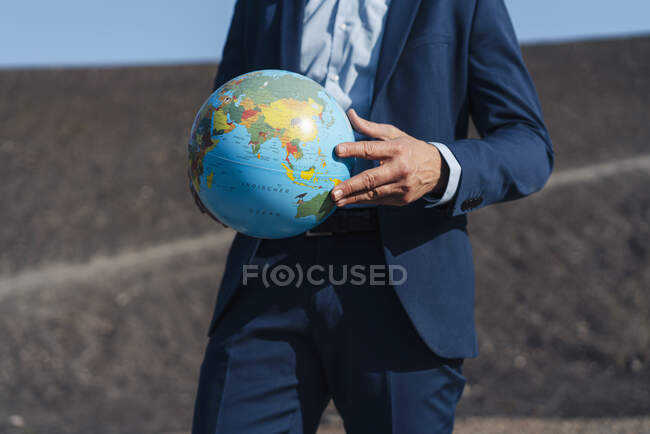 Primer plano del hombre de negocios maduro sosteniendo un globo en una punta de mina en desuso - foto de stock