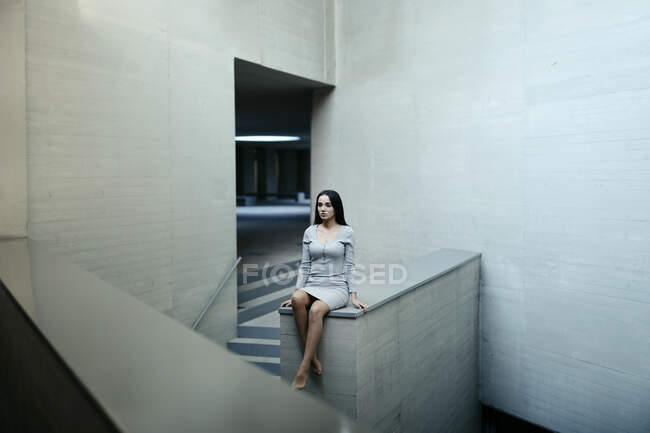 Thoughtful woman sitting on concrete wall — Stock Photo