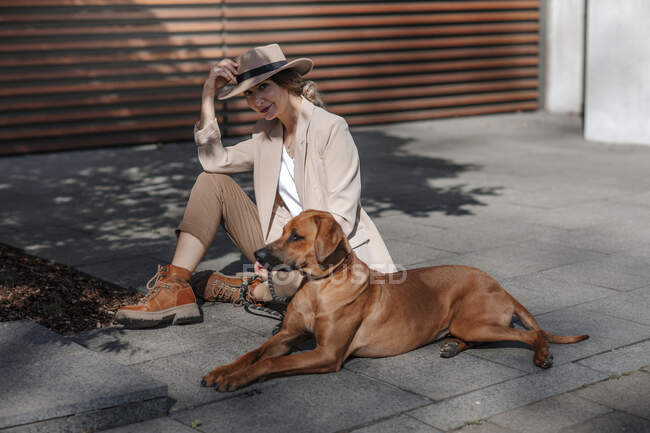 Femme à la mode avec son chien dans la ville — Photo de stock
