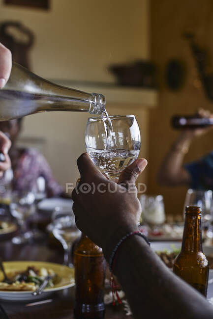 Gehackte Hand eines Mannes gießt Wasser für Freund am Esstisch — Stockfoto