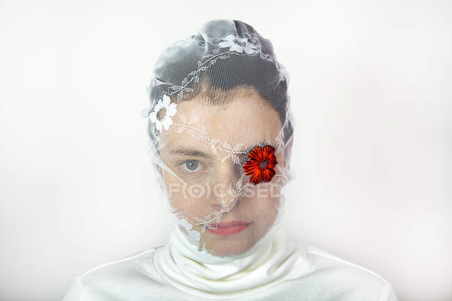 Portrait de jeune femme portant un voile blanc avec une fleur rouge couvrant un œil — Photo de stock