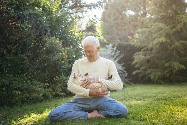 Uomo anziano coccole con il suo gatto in giardino — Foto stock