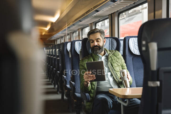 Чоловік сидить у потязі, користуючись планшетом. — стокове фото