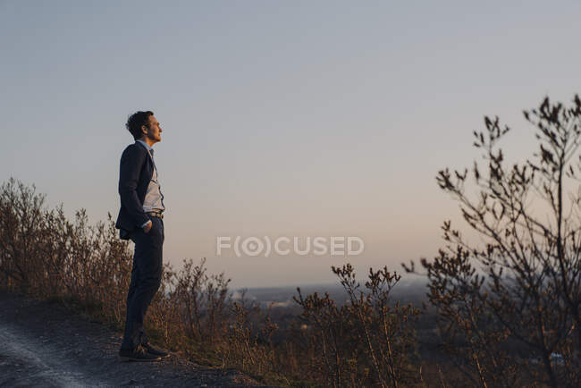 Homme d'affaires mature debout sur une pointe de mine désaffectée au coucher du soleil regardant la vue — Photo de stock