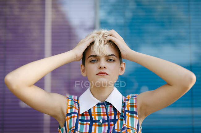 Porträt einer Teenagerin mit der Hand im Haar, die ein buntes Kleid mit einer bunten Glasscheibe im Hintergrund trägt — Stockfoto