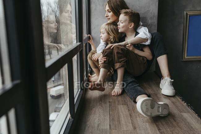 Longitud completa de la familia mirando a través de la ventana en casa - foto de stock