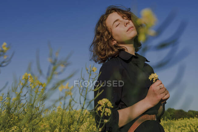 Portrait d'une adolescente avec les yeux fermés debout dans un champ de viol — Photo de stock