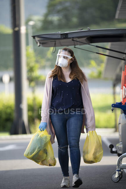 Kundin läuft mit Plastiktüte auf Supermarkt-Parkplatz — Stockfoto