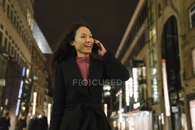 Happy young woman on the phone in the city at night, Frankfurt, Germany — Stock Photo
