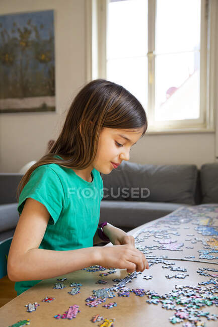 Menina fazendo um quebra-cabeça em casa — Fotografia de Stock