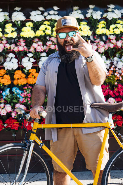 Portrait of bearded man with fixie bike sticking out tongue and showing Rock And Roll Sign — Stock Photo
