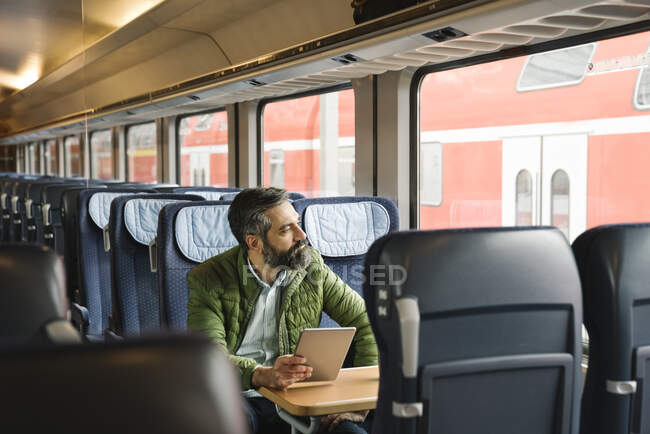 Человек, сидящий в поезде с табличкой — стоковое фото
