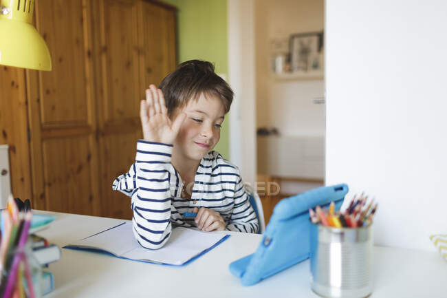 Мальчик занимается домашним обучением и использует планшет дома — стоковое фото