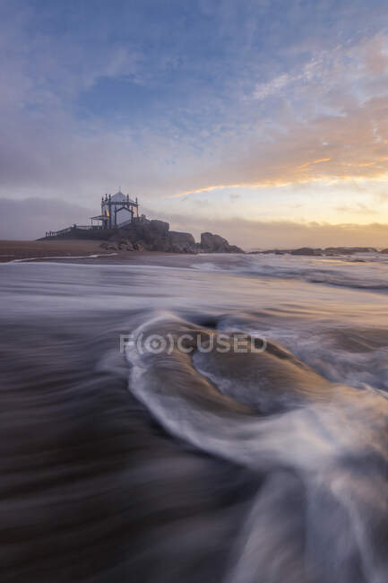 Portugal, Porto District, Vila Nova de Gaia, long extrations of Praia de Miramar and Capela do Senhor da Pedra at moody sunset — стокове фото