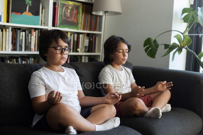 Siblings sitting on couch meditating — Stock Photo