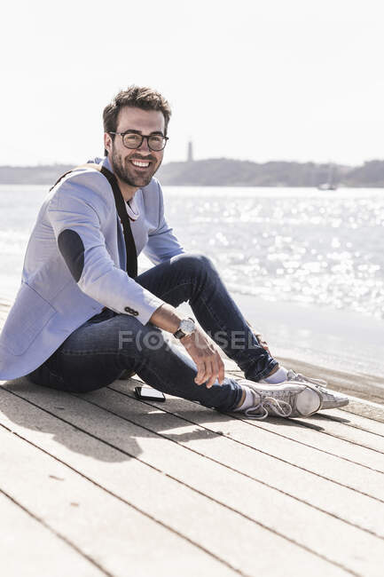 Retrato de um jovem feliz sentado à beira-mar — Fotografia de Stock