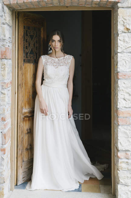 Young woman in wedding dress walking through door — Stock Photo