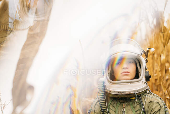 Молодой космонавт стоит на иссохшем кукурузном поле — стоковое фото