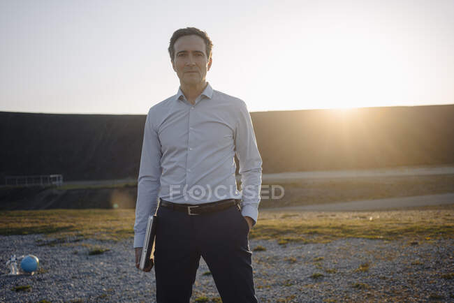 Портрет зрілого бізнесмена, який тримає ноутбук на відключеному мінеті під час заходу сонця — стокове фото