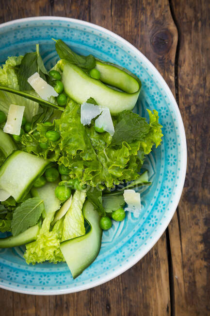 Plate of salad with green peas, mint, cucumber, Parmesan cheese and Lollo Bionda lettuce — Stock Photo