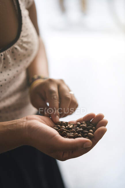 Close-up of woman with coffee beans in her hand — Stock Photo