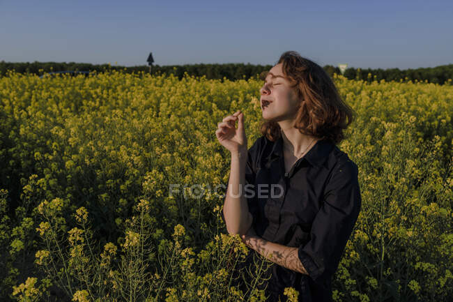 Portrait of happy teenage girl with eyes closed standing in rape field — Stock Photo