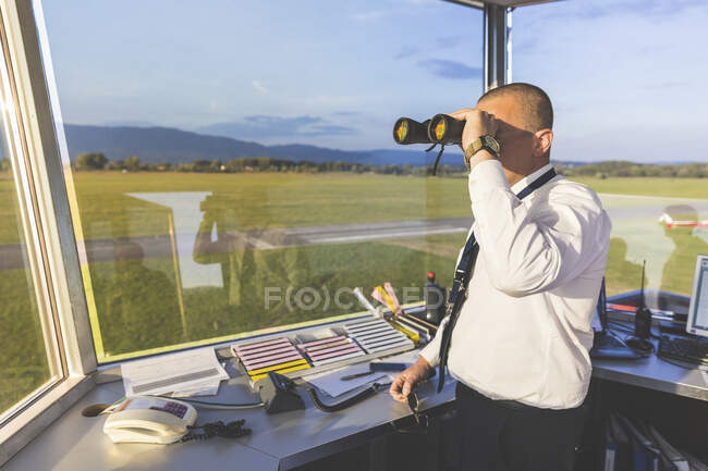 Pilot standing in control tower, using binoculars — Stock Photo