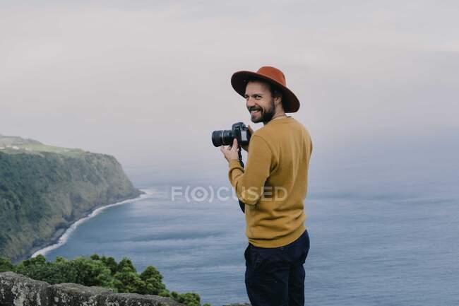 Uomo sorridente con una macchina fotografica sulla costa dell'isola di Sao Miguel, Azzorre, Portogallo — Foto stock
