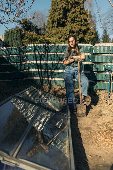Junge Frau mit Garten steht vor selbstgebautem Gewächshaus — Stockfoto