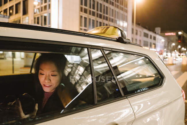 Young woman using smartphone in a taxi at night, Frankfurt, Germany — Stock Photo