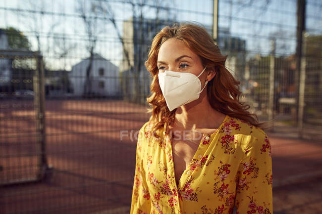 Портрет рыжеволосой женщины в маске FFP2 в городе — стоковое фото