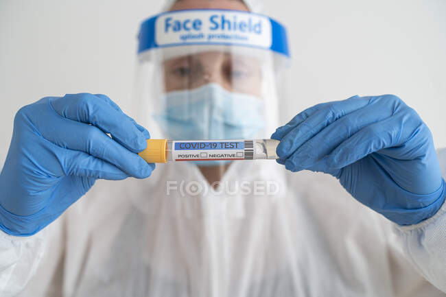 Woman in protective wear holding covid-19 test — Stock Photo
