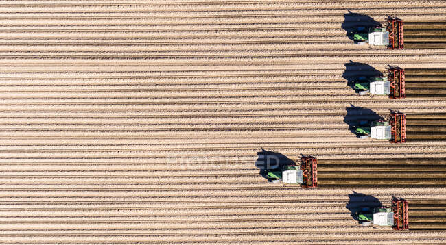 Germany, Hesse, Bergstarsse, Aerial view of tractors plowing brown field in spring — Stock Photo