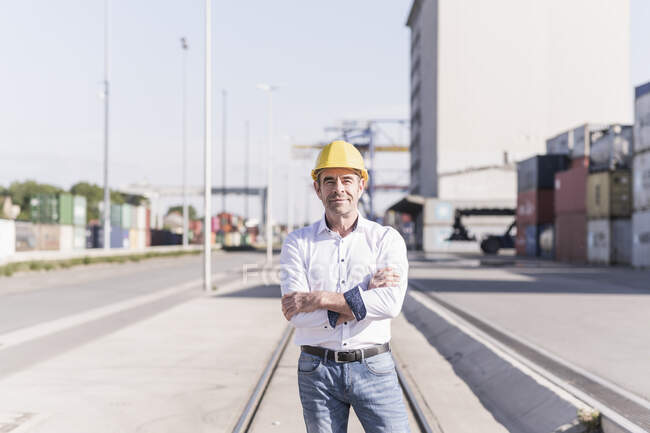 Ritratto di uomo d'affari che indossa un casco di sicurezza davanti al sito industriale — Foto stock