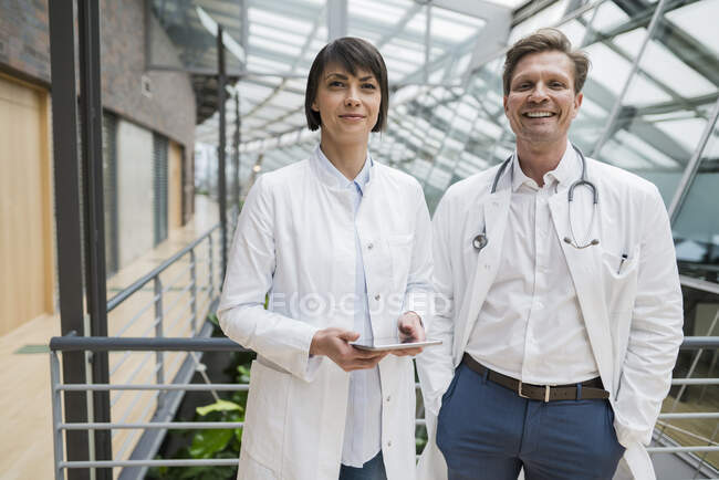 Two doctors standing in atrium, holding digital tablet — Stock Photo