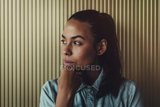 Primer plano de la joven reflexiva mirando hacia otro lado contra la pared - foto de stock