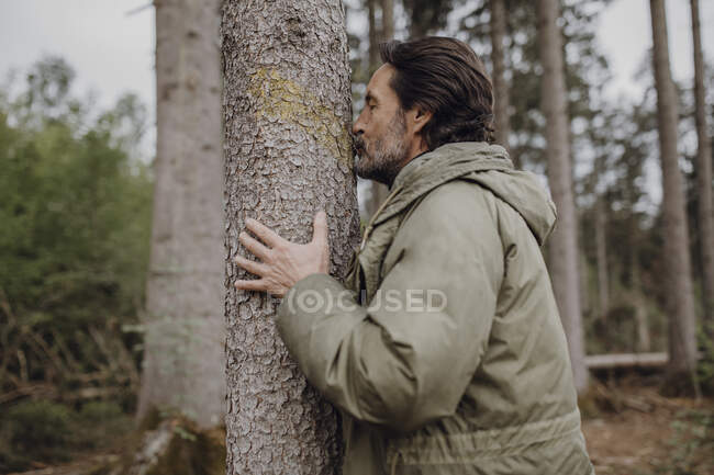 Mature hiker kissing tree trunk — Stock Photo