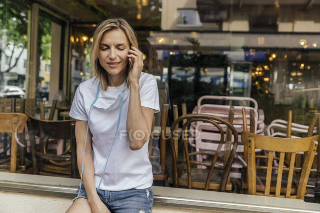 Portrait de femme au téléphone avec masque de protection devant un café fermé — Photo de stock