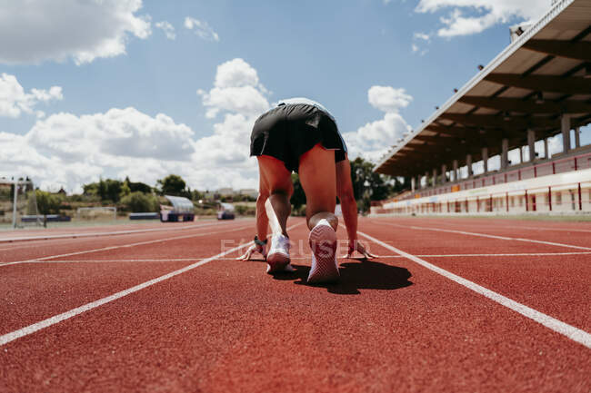 Male athlete in starting position on tartan track — Stock Photo
