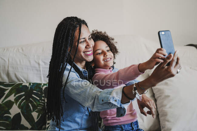 Happy mother and her little daughter taking selfie with smartphone at home — Stock Photo