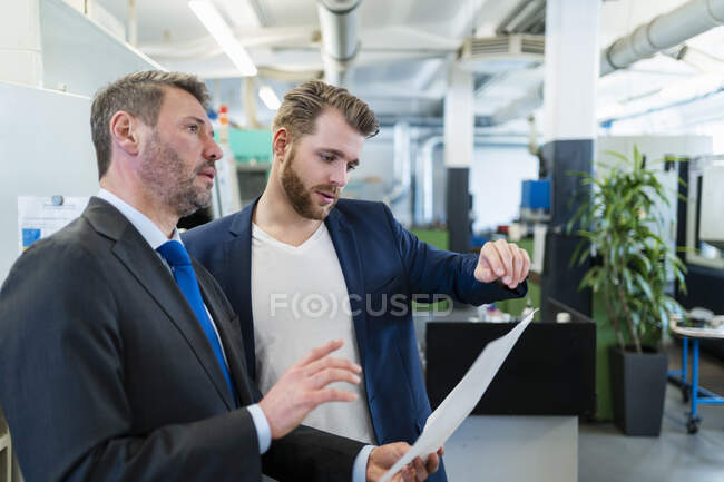 Два бизнесмена на рабочем совещании на заводе обсуждают план — стоковое фото